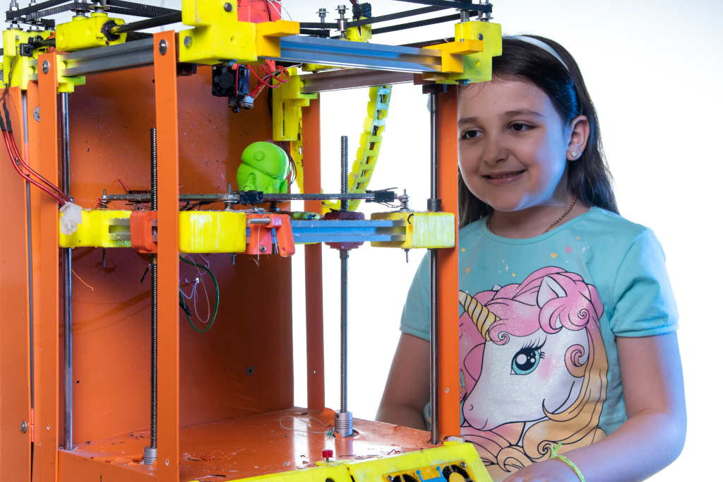 Estudante ao lado de uma impressora 3D